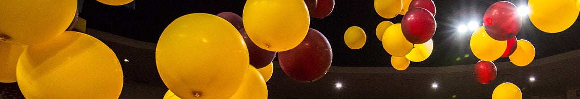 maroon and gold balloons floating in the air 