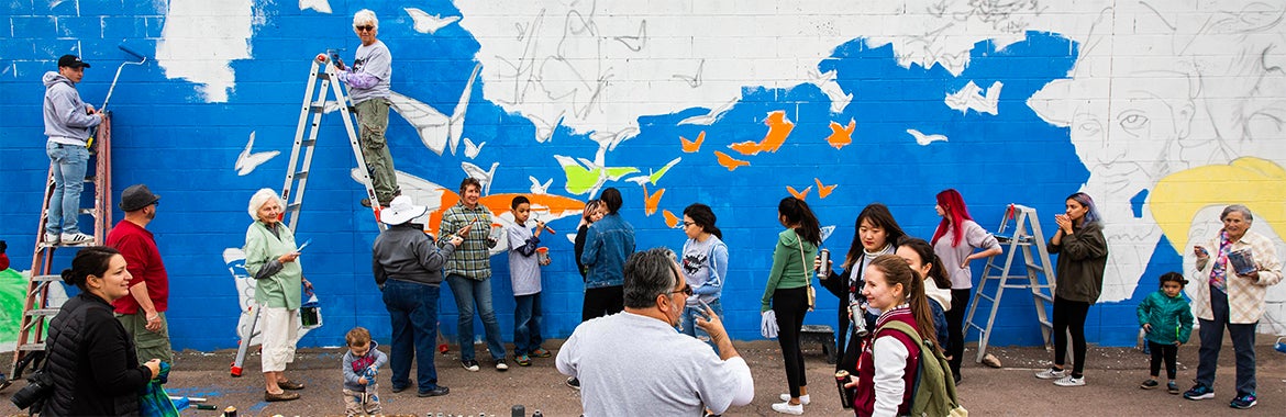 group of people painting a blue mural with butterflies 