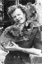 Nina Mason Pulliam headshot - black and white photo, fair-skinned woman, smiling, button-up shirt, holding two koalas 